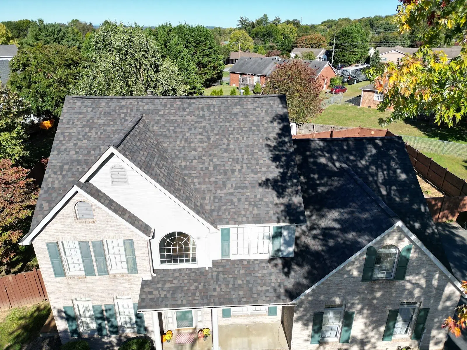 Architectural shingle roof replacement on a complex light-brick home roofline