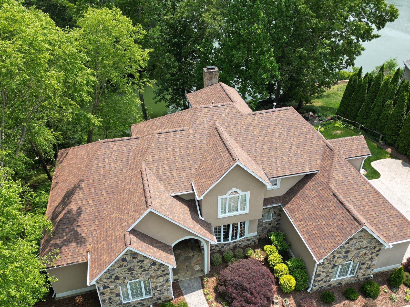 Drone view of a luxury multi-gable home with a new shingle roof