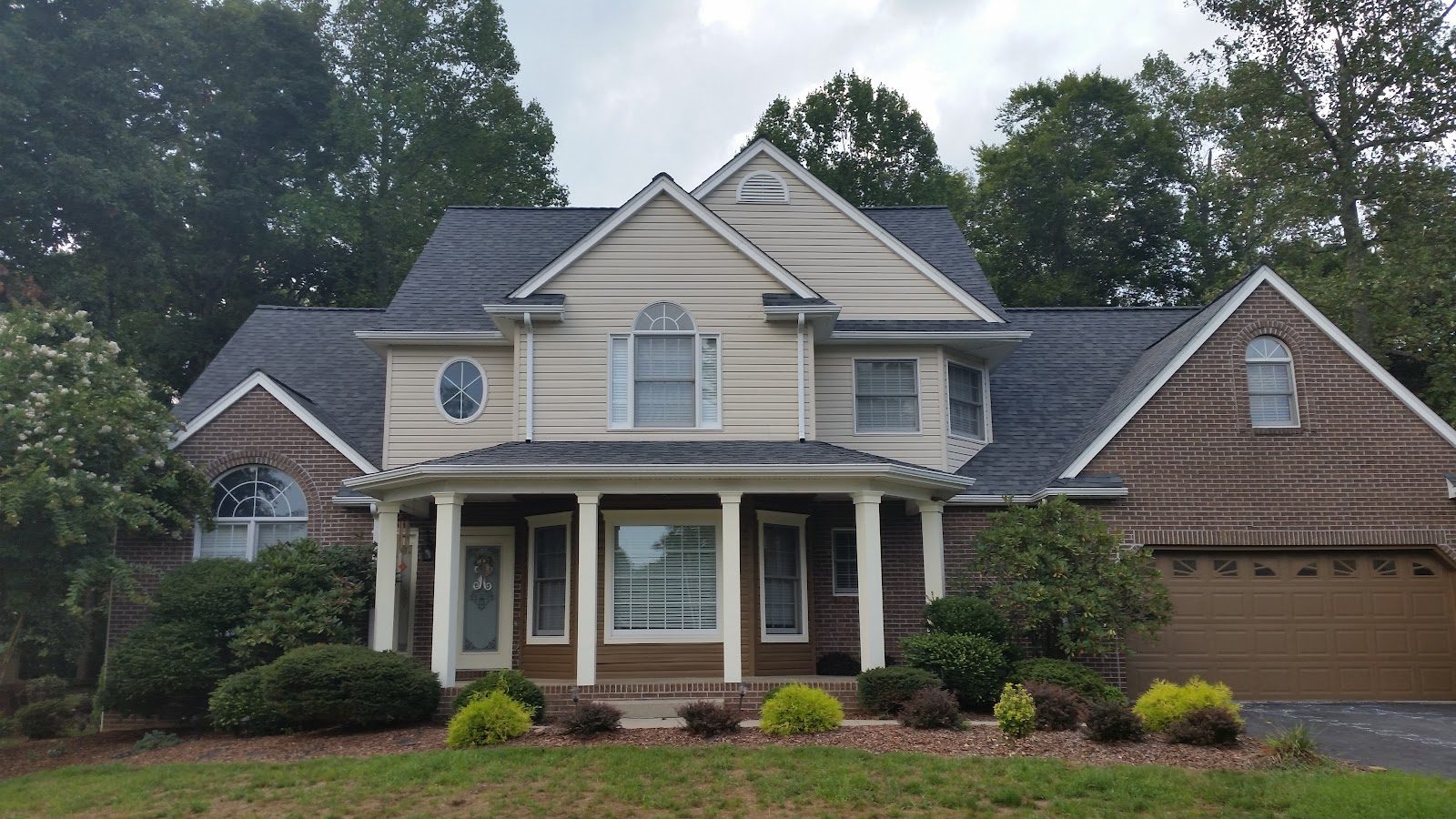 Completed asphalt shingle roof replacement on a cream and brick home in the Tri-Cities, TN