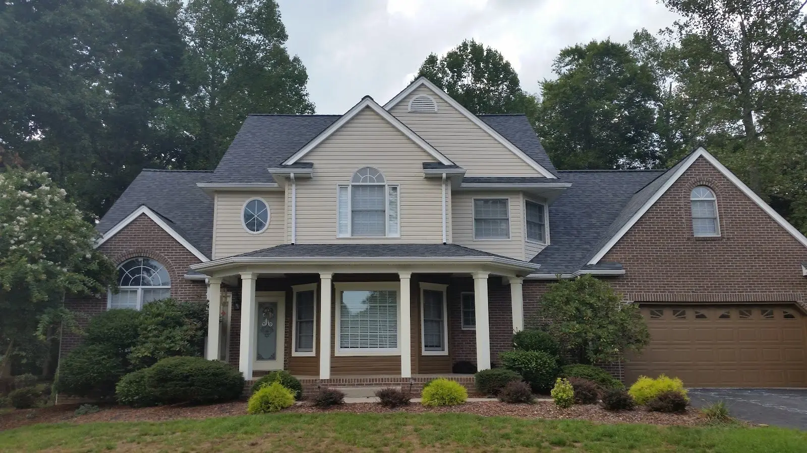 Completed asphalt shingle roof replacement on a cream and brick home in the Tri-Cities, TN